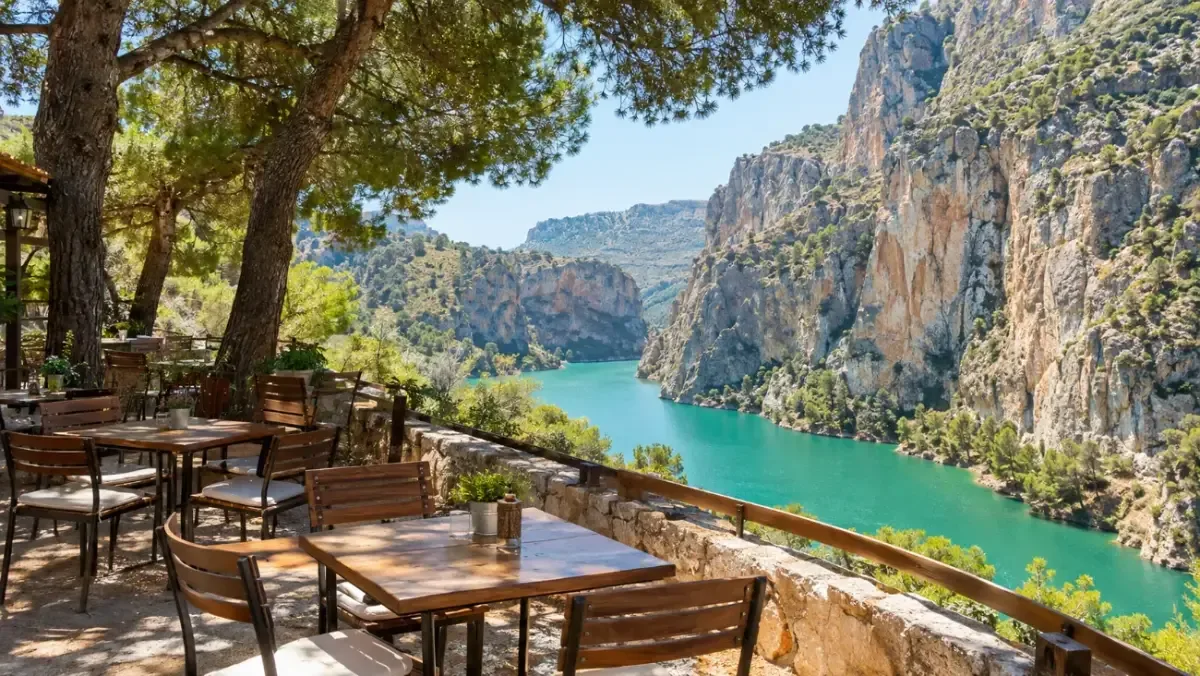 Eine Restaurantterrasse an einem türkisfarbenen Stausee mit Kiefern